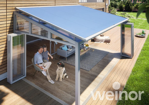 Moderne Terrassenüberdachung aus Glas mit Markise, Familie und Hund auf Holzterrasse.