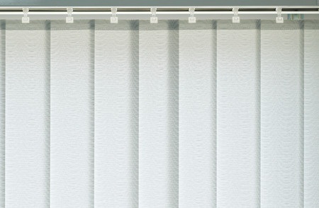 Vertikale Lamellen-Jalousie in heller Farbe als moderner Sicht- und Sonnenschutz am Fenster.