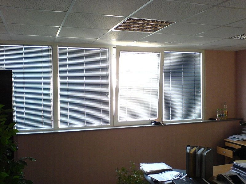 Modernes Büro mit großen Fenstern, Jalousien und Schreibtisch für angenehmes Arbeiten.