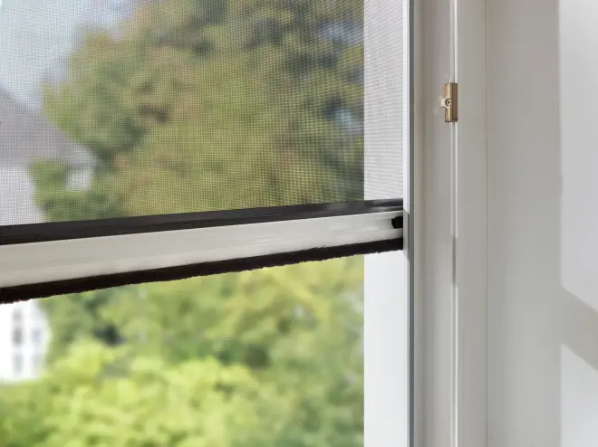 Insektenschutz Fliegengitter am geöffneten Fenster mit Blick ins Grüne und Tageslicht.